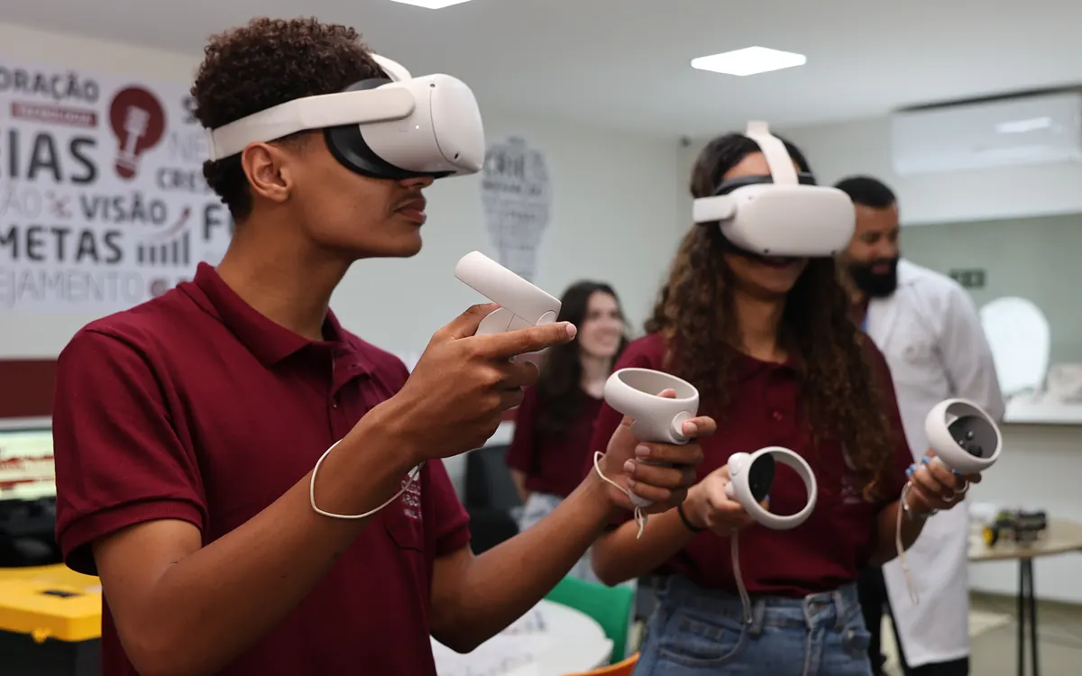Alunos de uniforme usam óculos de realidade virtual no laboratório de tecnologia